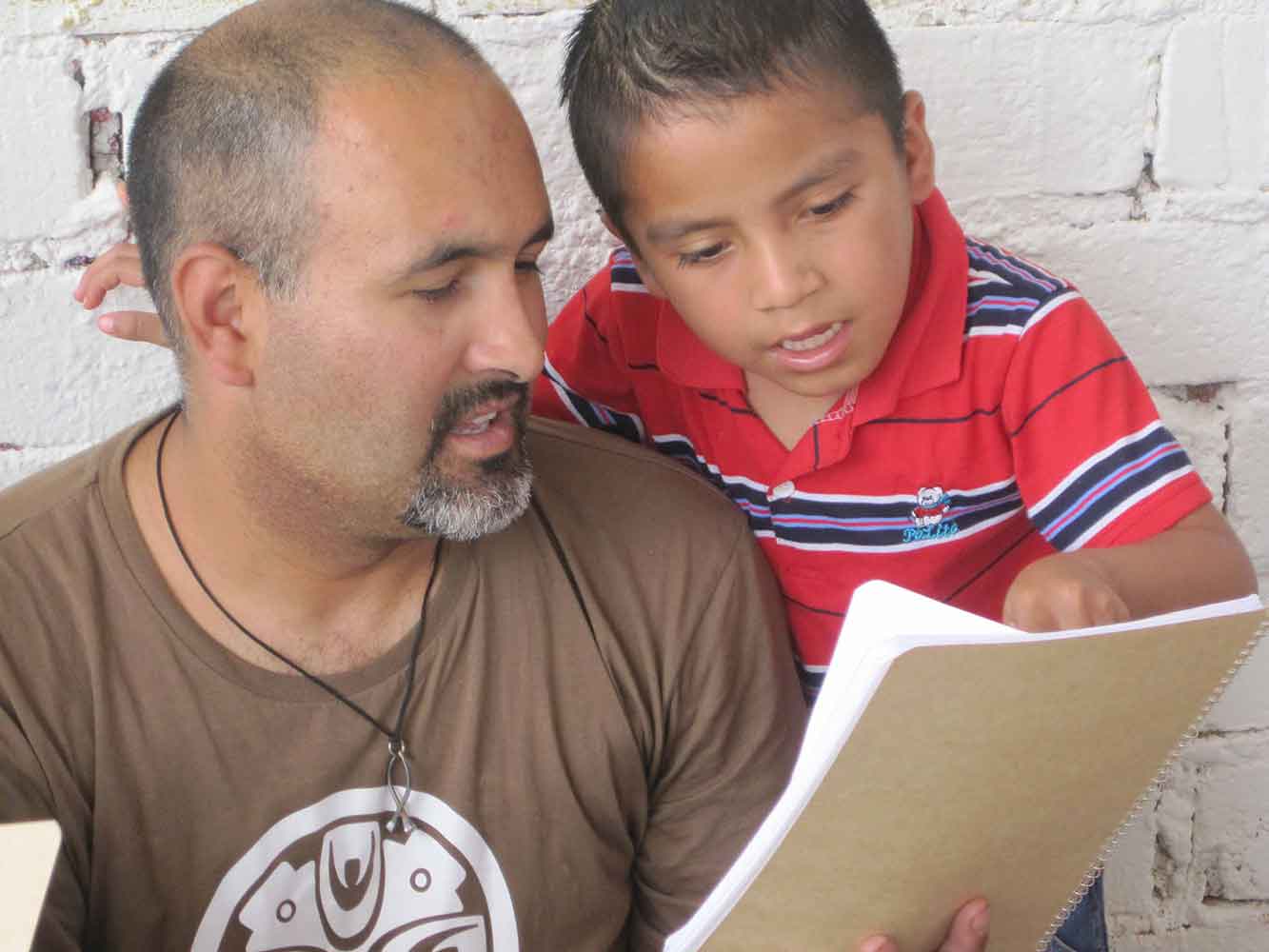 A student shows a page from his notebook to his son